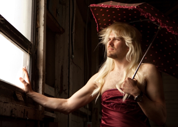 Forced feminization of man in dress with parasol.