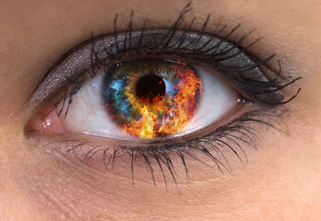 Fire for BDSM branding reflected in woman's eye.
