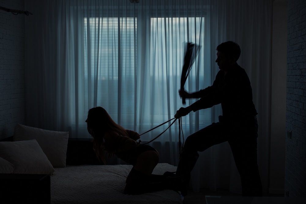 erotic spanking scene with man using flogger on bound woman.