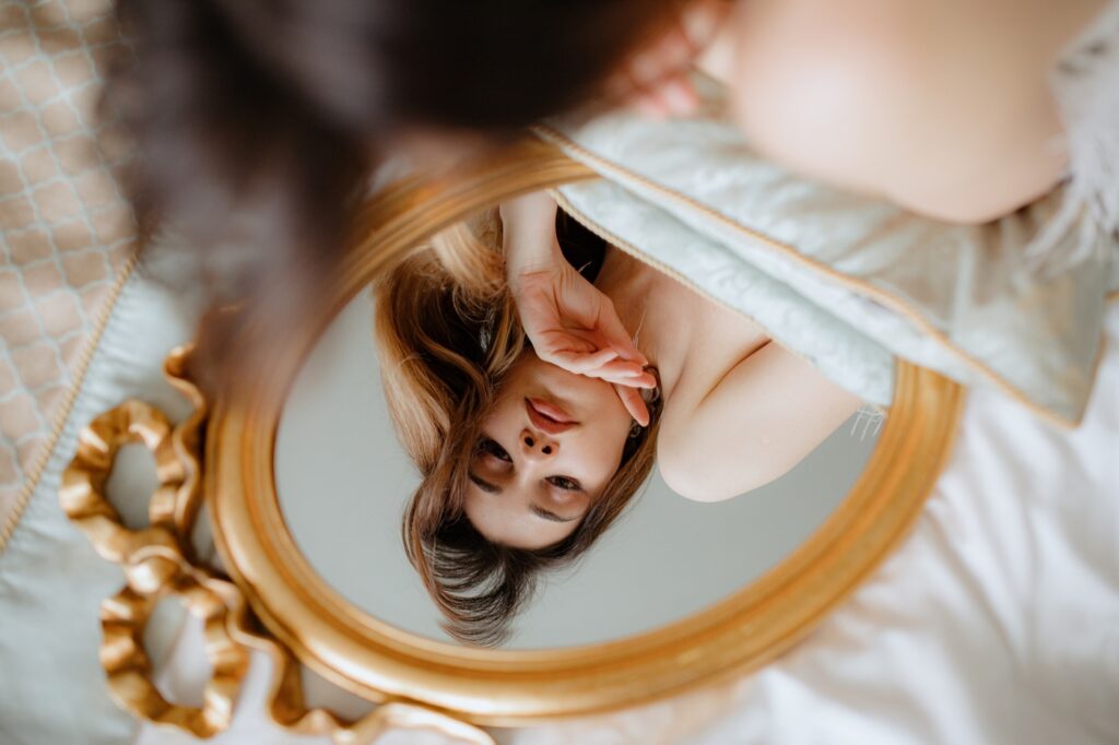 Brunette Lying in Bed Looking at Reflection in Mirror