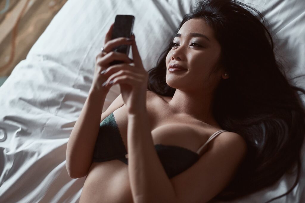 Sexy Asian Woman in Lingerie Reading Phone